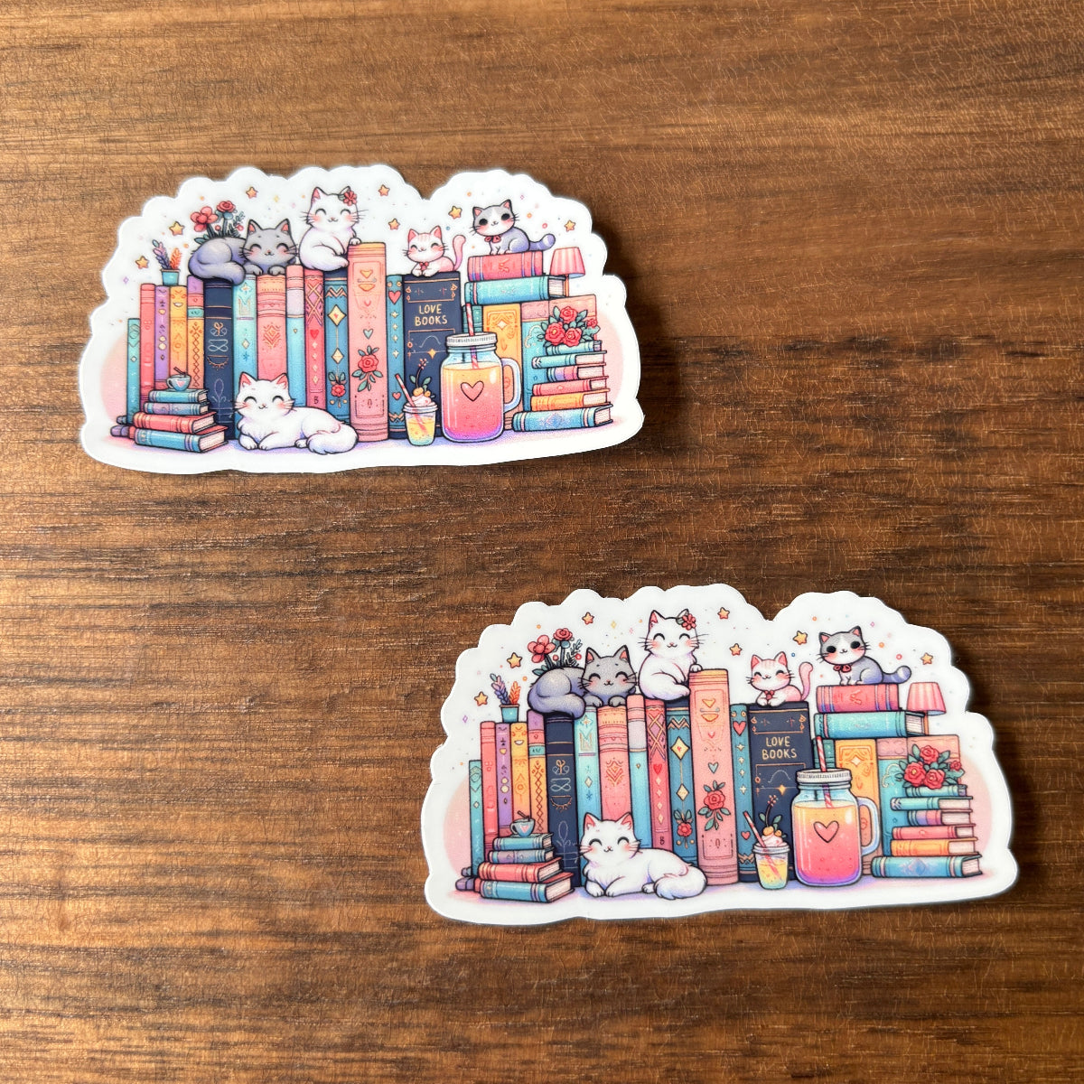 Two identical stickers of cats on books with a wooden background