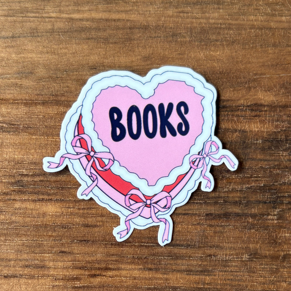Heart-shaped sticker with 'BOOKS' text on a wooden surface